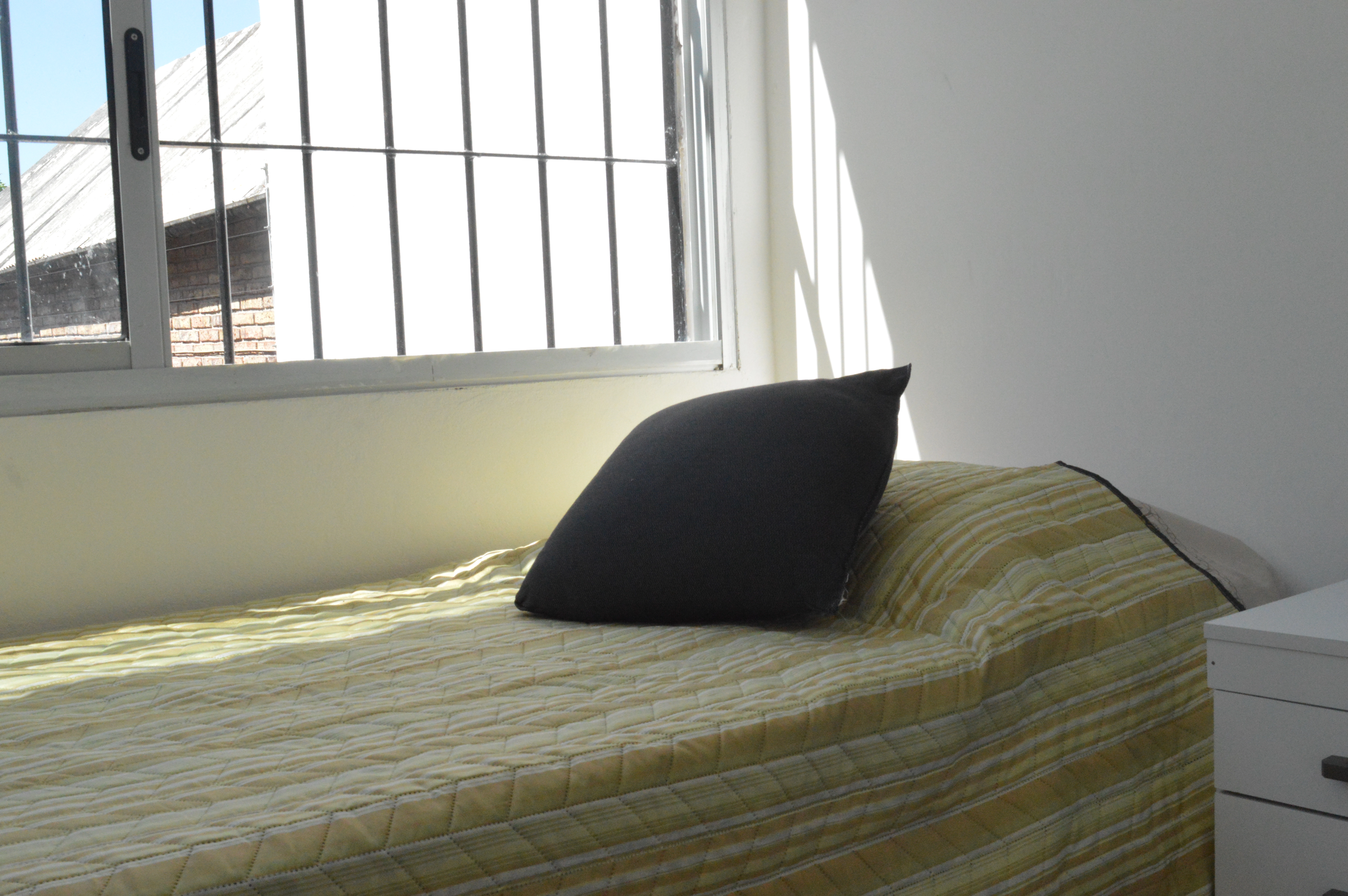 Habitación individual con cama y ventana luminosa del Residencial Lumina